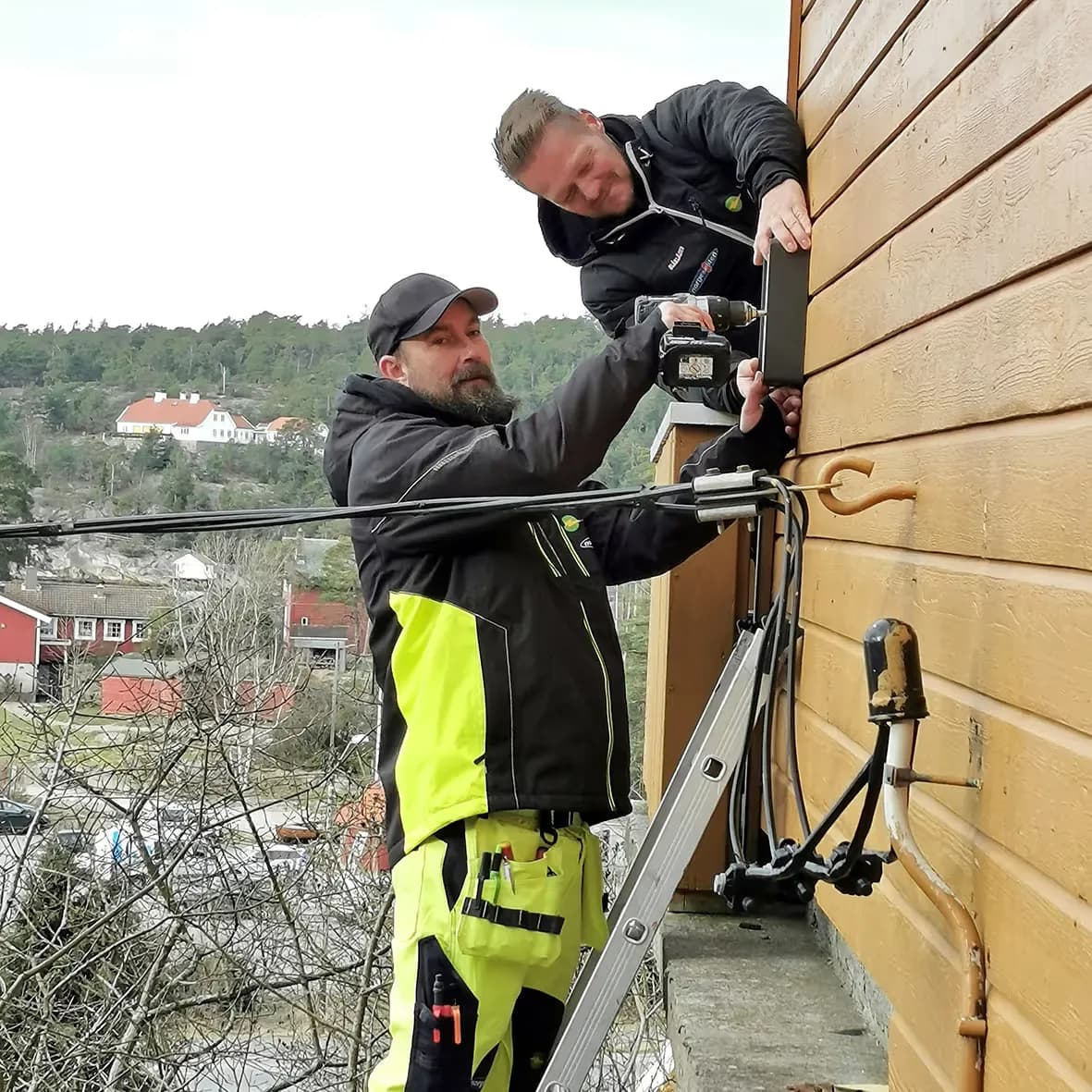 To elektrikere fra LYN Elektro monterer en ladeboks på en husvegg